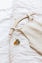 Minimalist baby clothing in soft fabrics laid out on a light wooden surface