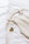 A wooden hanger holds a beige linen garment, laid out on a soft white surface, next to a yellow pacifier with a gray rim.