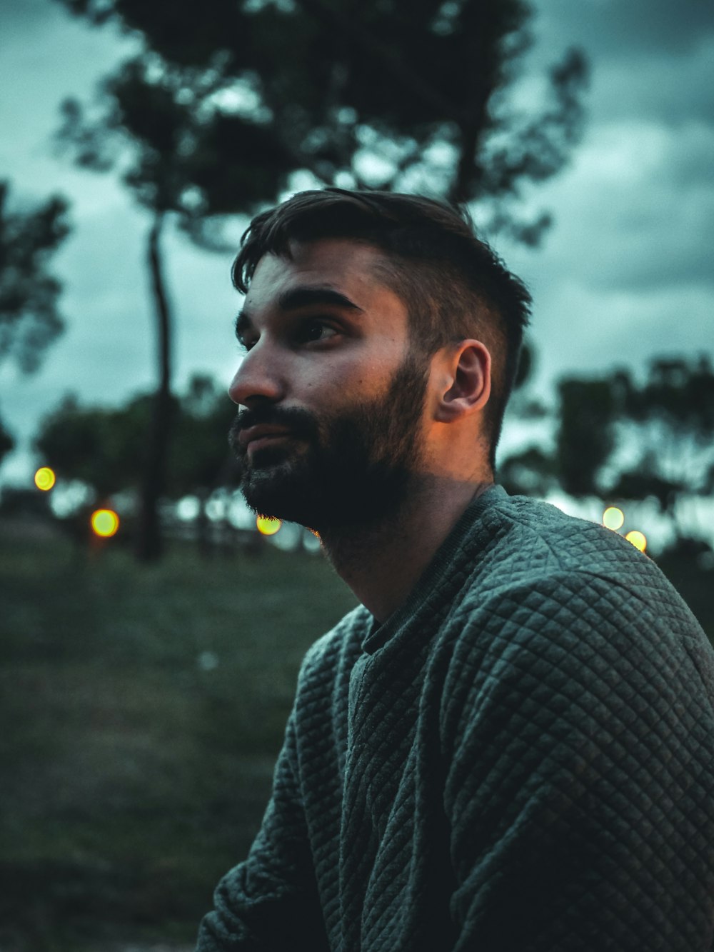 a man with a beard sitting in a park