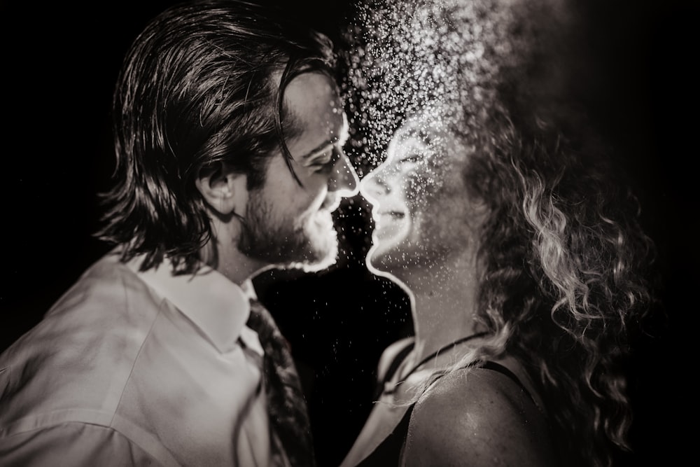 a man and a woman are kissing under a spray of water