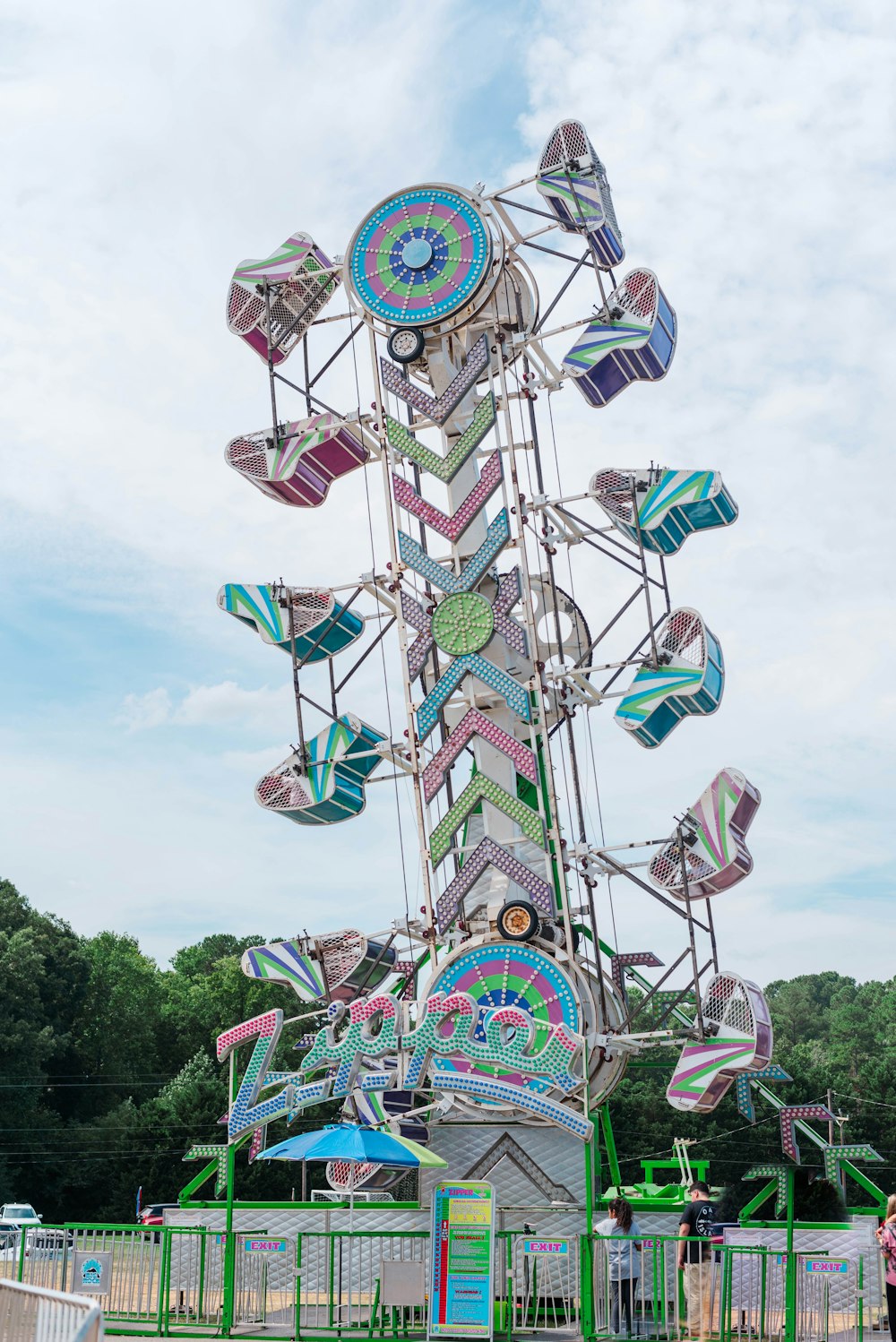 a colorful ferris wheel with people standing around it