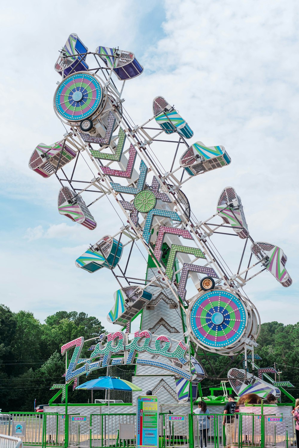 a ferris wheel in a park with people standing around it