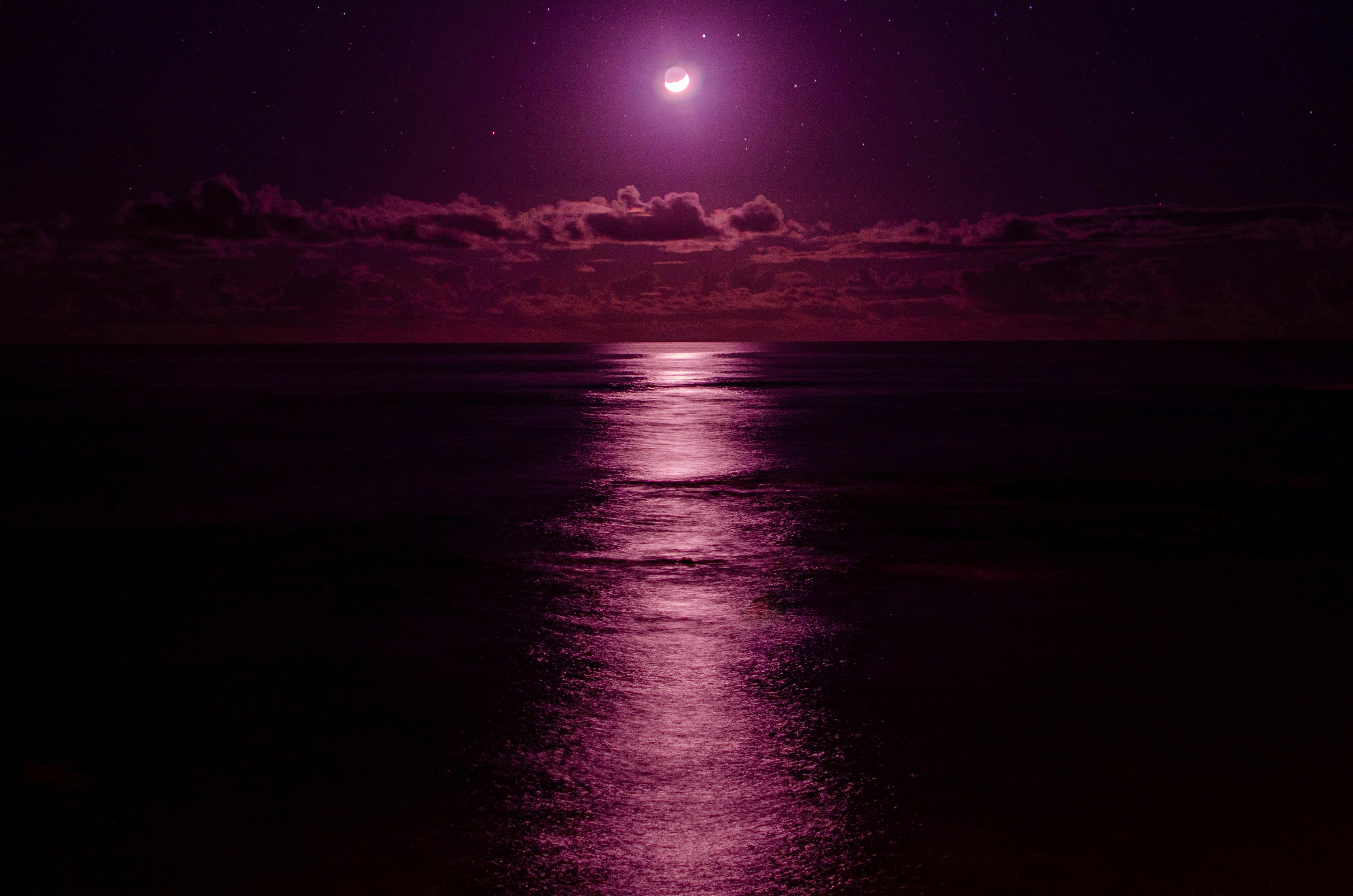a full moon is seen over the ocean at night
