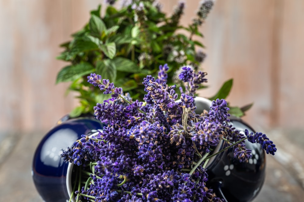 a blue vase filled with purple flowers on top of a wooden table