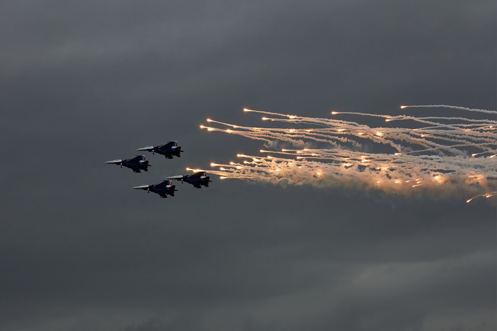 a group of fighter jets flying through a cloudy sky