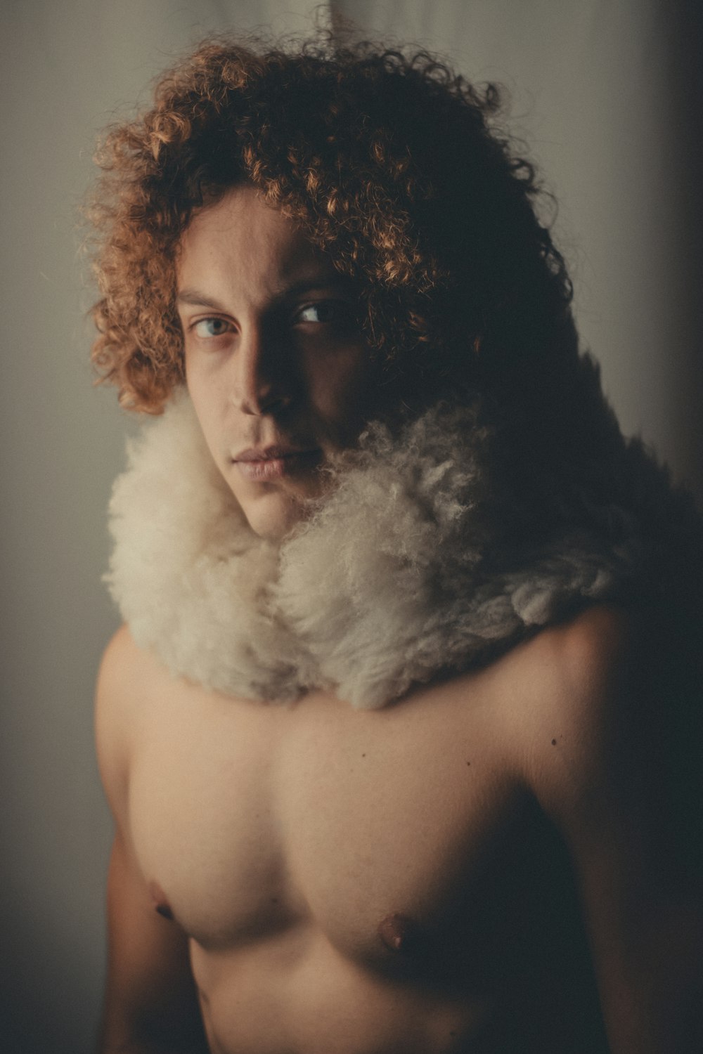 a shirtless man with curly hair and a scarf around his neck