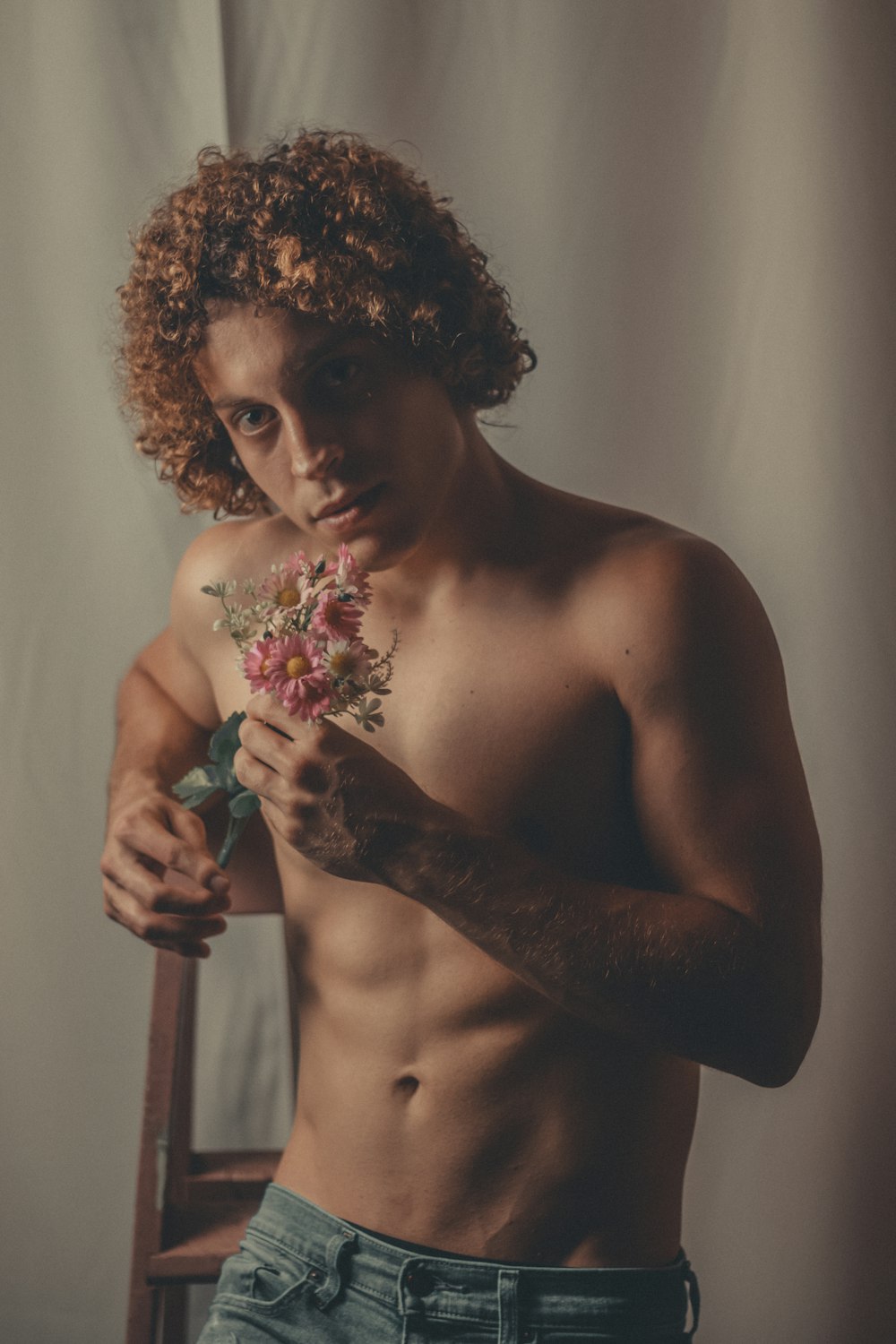 a shirtless man holding a bunch of flowers