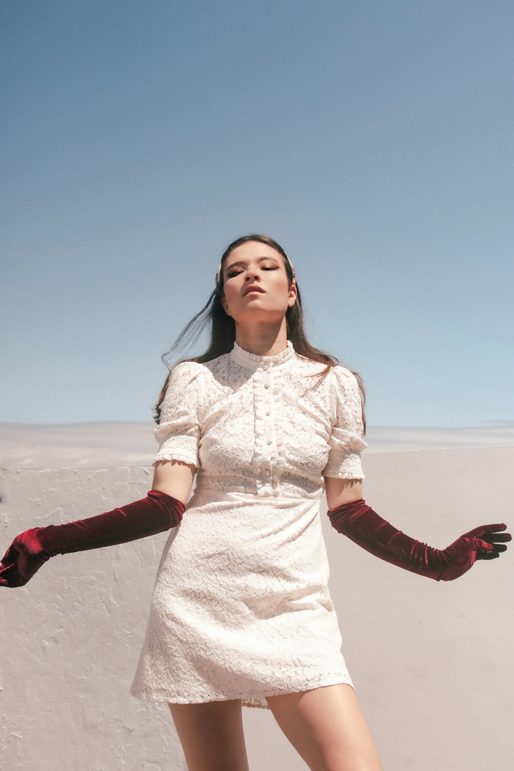 a woman in a white dress and red gloves