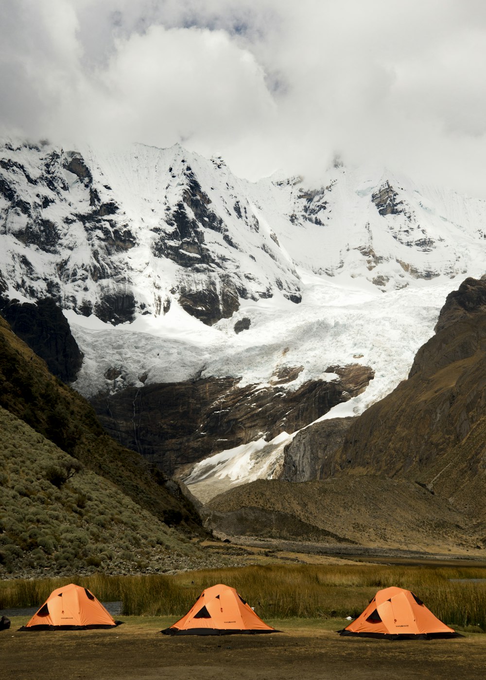 a group of tents set up in front of a snowy mountain