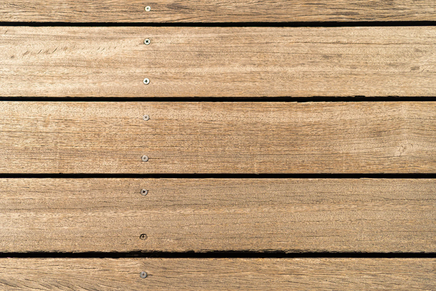 Close-up of weathered wooden deck boards showing wear at the fasteners