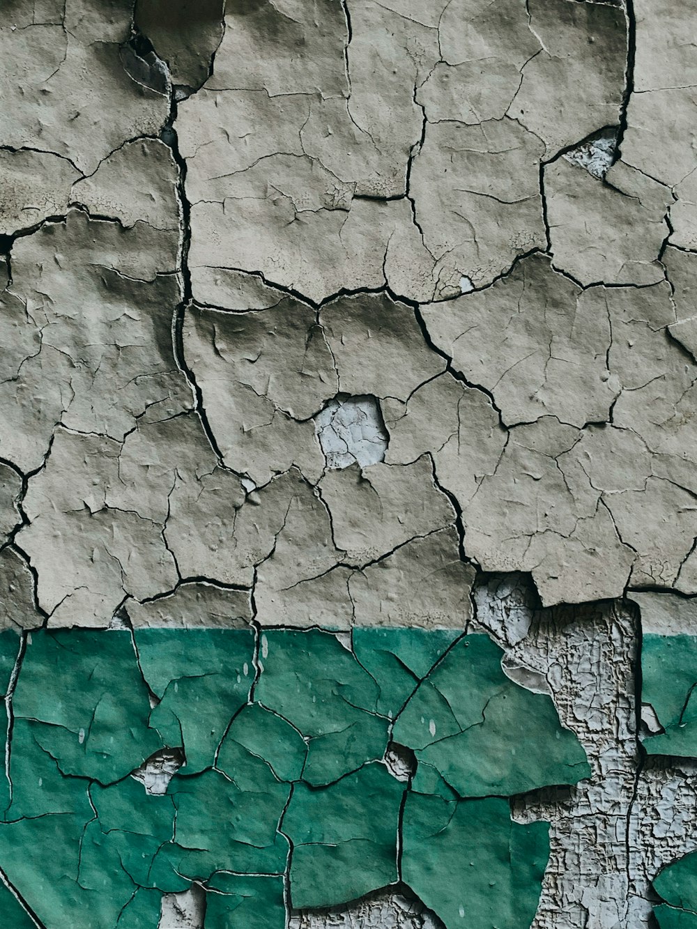 a close up of a cracked wall with green paint