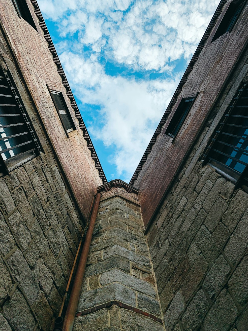 a tall brick building with two windows and a sky background