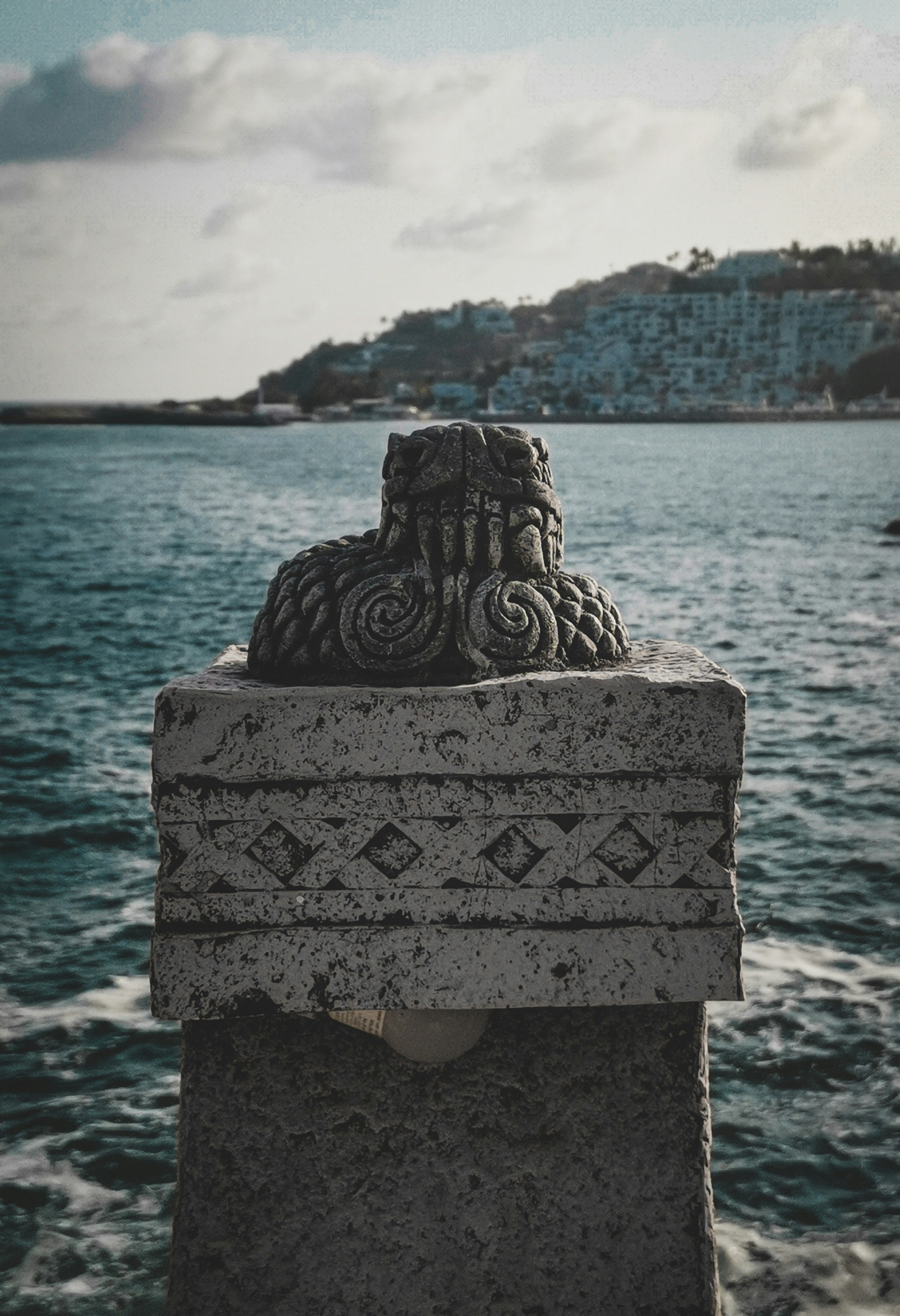 a stone statue sitting on the edge of a body of water