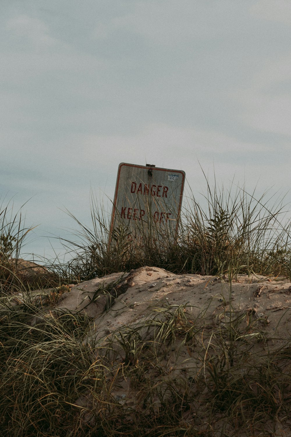 a rusted sign sitting on top of a sandy beach
