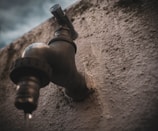 Close-up of a plumber tightening a shiny new faucet in a rustic French kitchen.