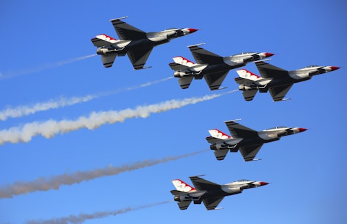 a group of jets flying through a blue sky