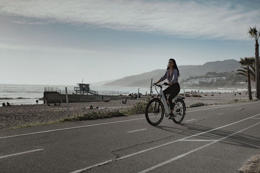 Una mujer montando en bicicleta por una calle junto al océano