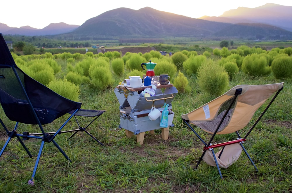 a couple of lawn chairs sitting on top of a grass covered field