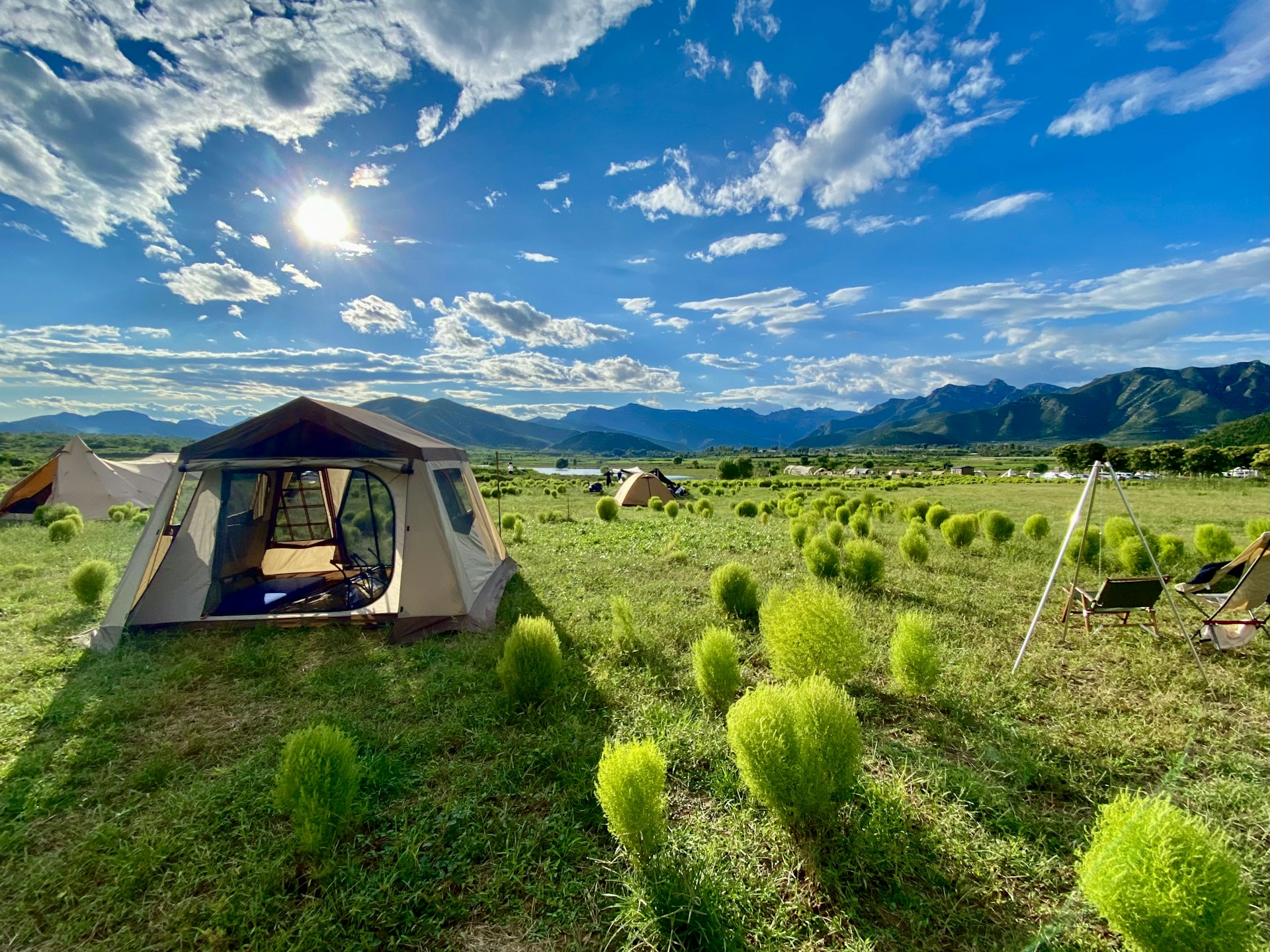 a tent set up in a field with mountains in the background