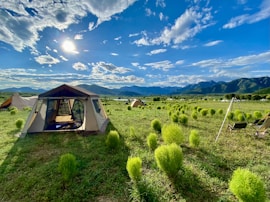 a tent set up in a field with mountains in the background