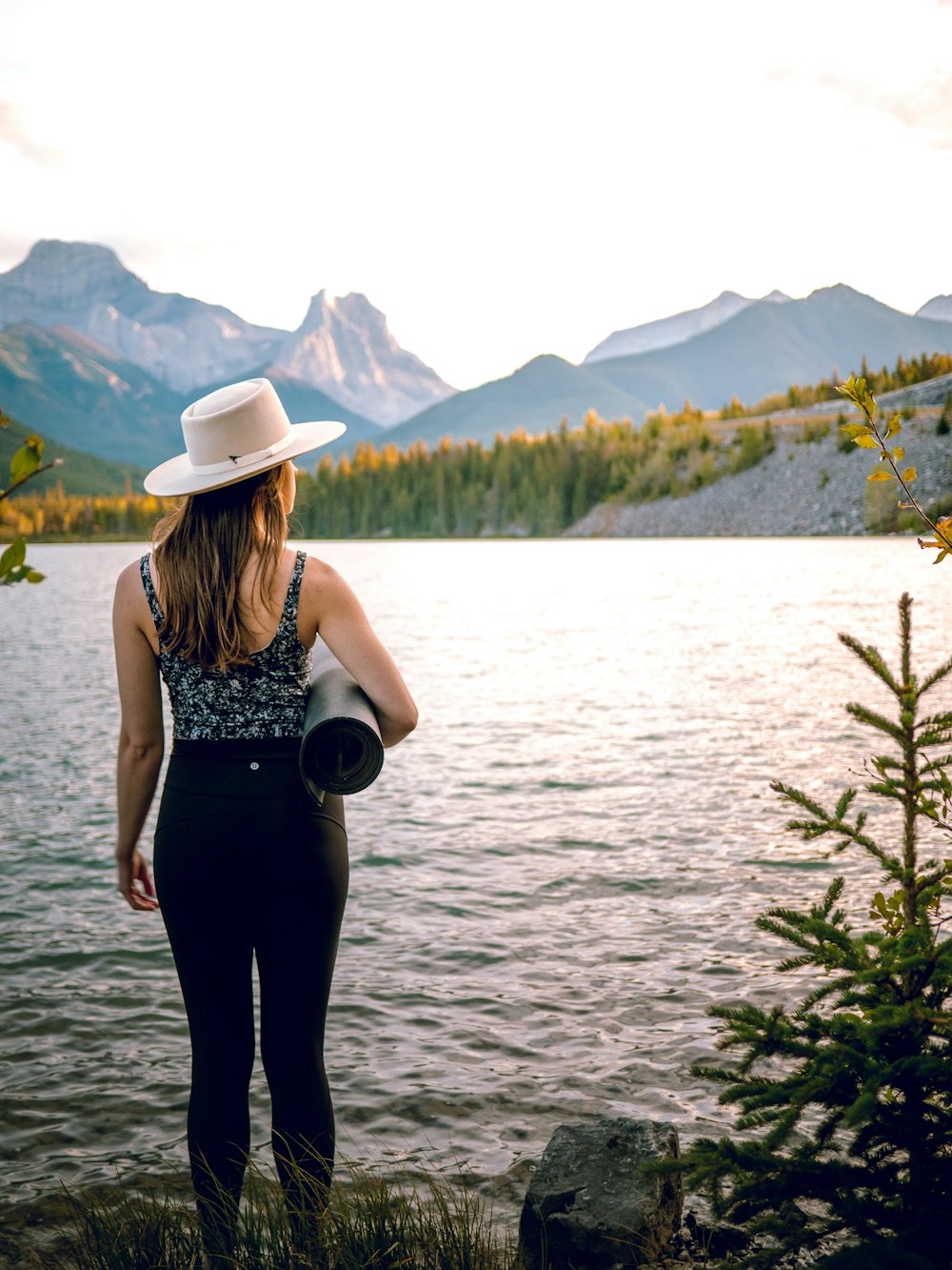 a woman wearing a hat looking out over a lake