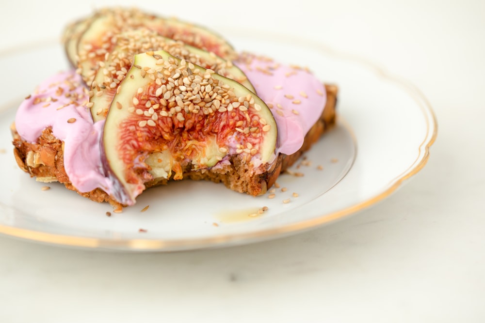 a white plate topped with a piece of cake covered in pink frosting