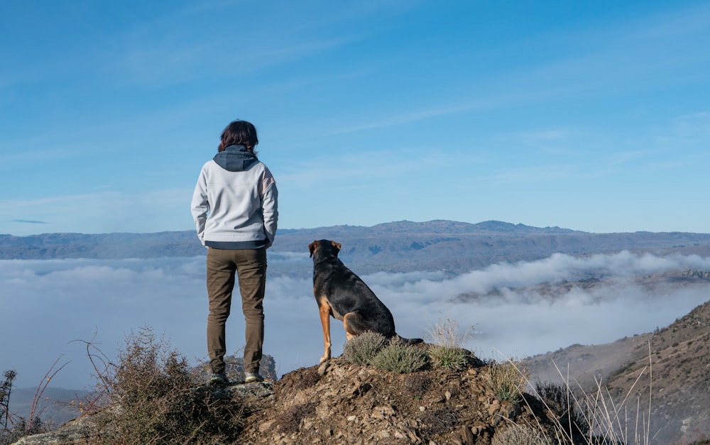 una persona in piedi sulla cima di una montagna con un cane