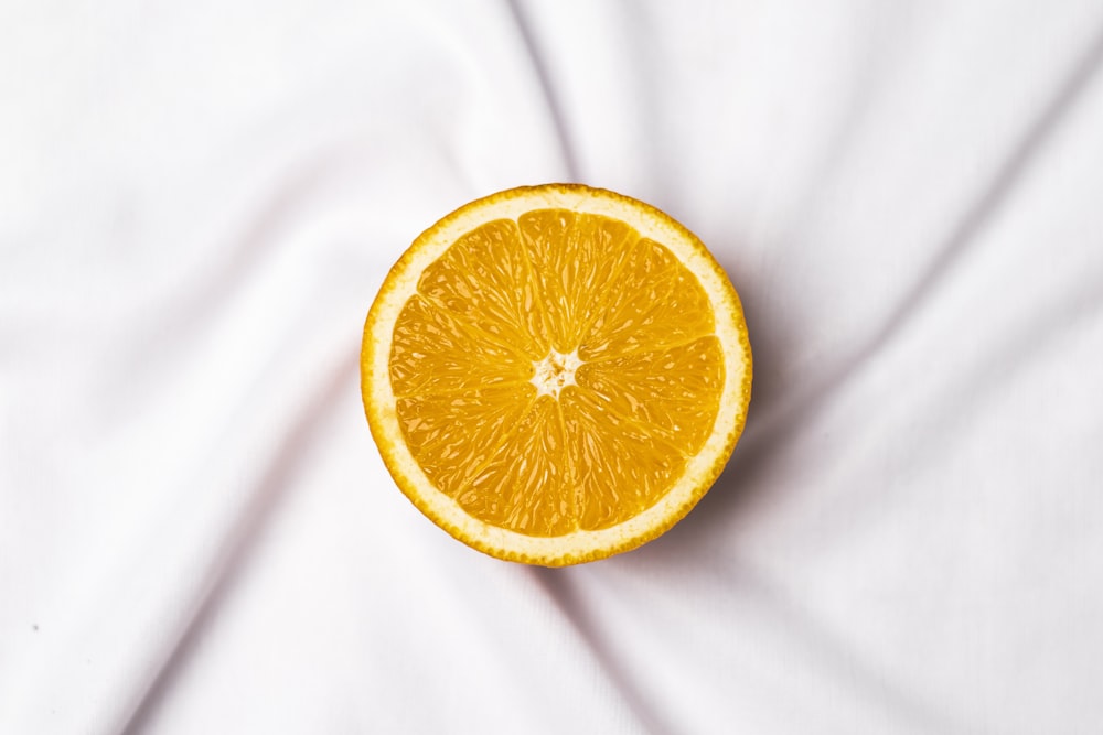 a half of an orange sitting on top of a white sheet
