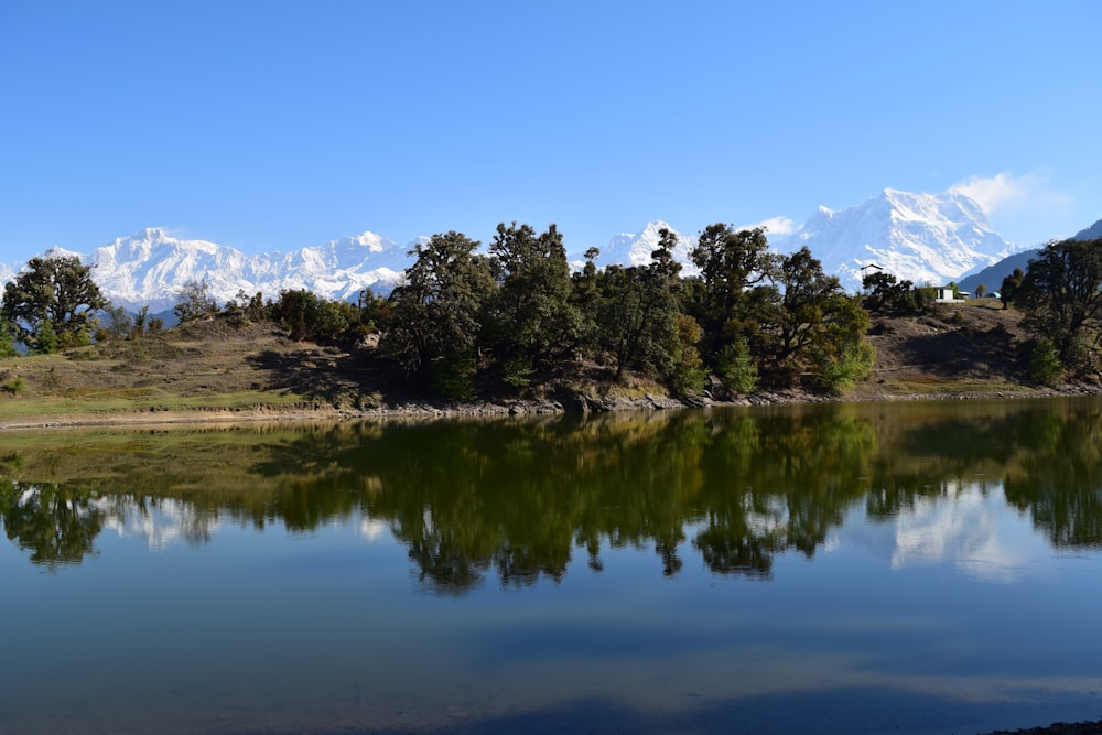 a lake surrounded by trees with a mountain in the background