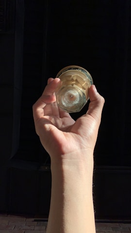 A hand holding a spotless glass cleaned with one of ejikef llc's cloths, sunlight reflecting off it.