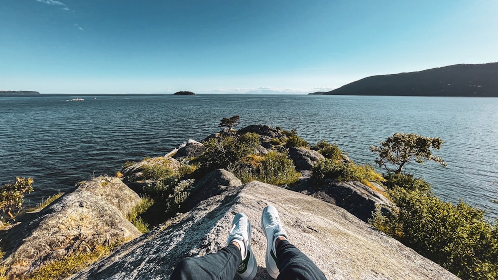 a person laying on top of a rock next to a body of water