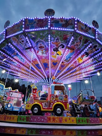 a brightly lit carnival ride with a colorful car