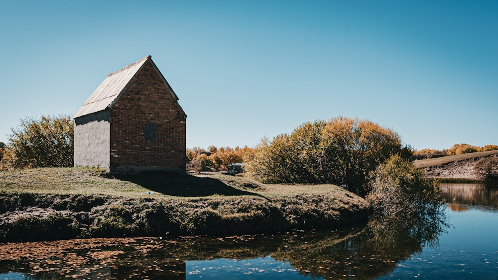 a small house sitting on top of a hill next to a body of water