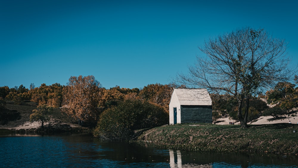a small house sitting on top of a hill next to a body of water