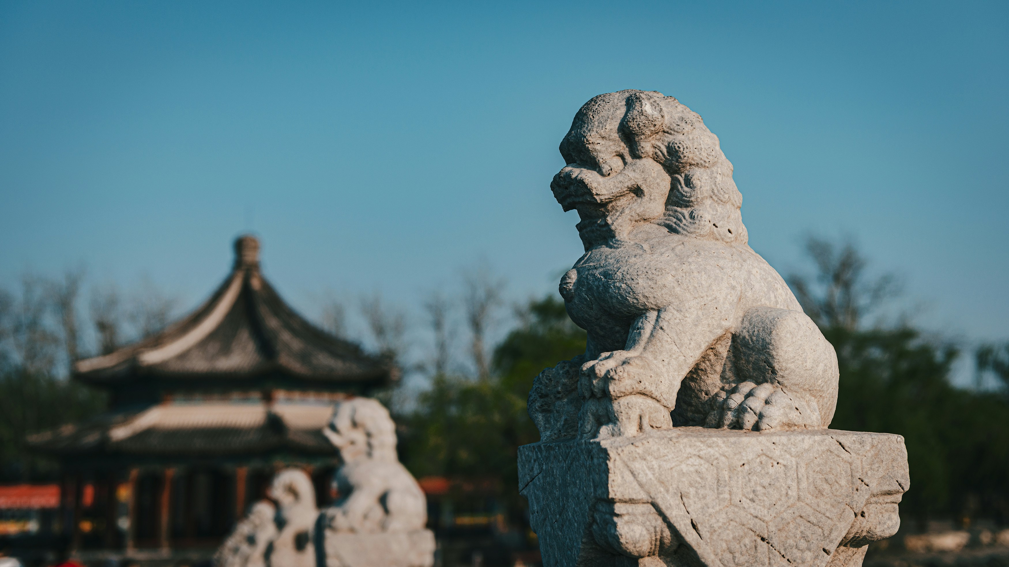 a stone lion statue in front of a pagoda, Beihai Park