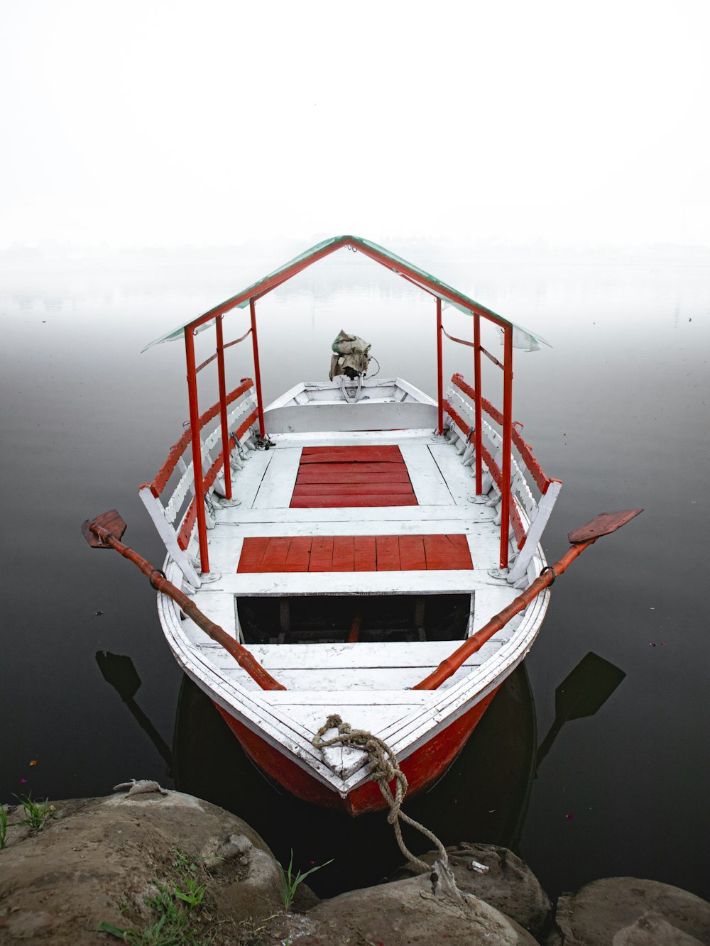 a red and white boat floating on top of a body of water