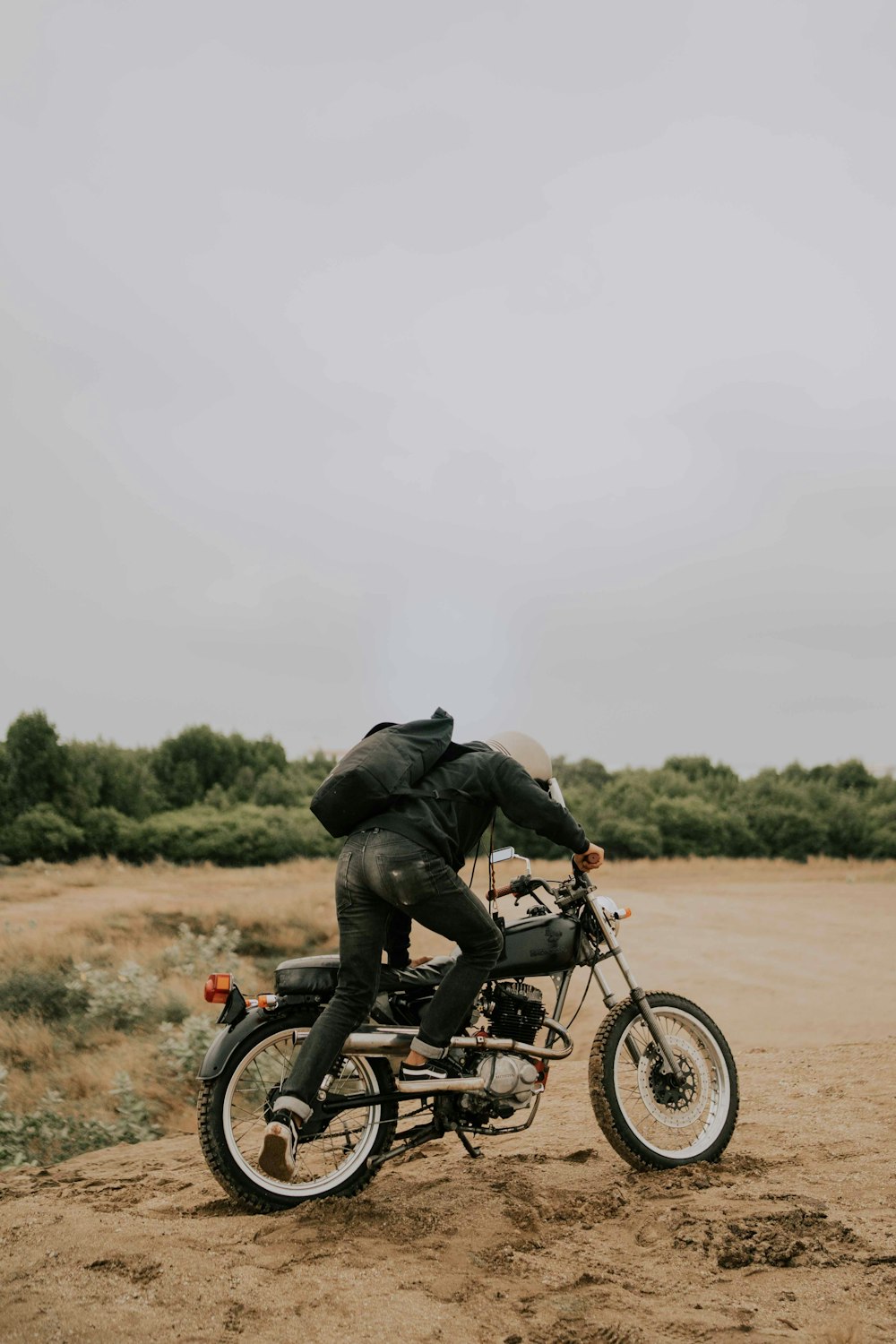 a man riding on the back of a motorcycle down a dirt road