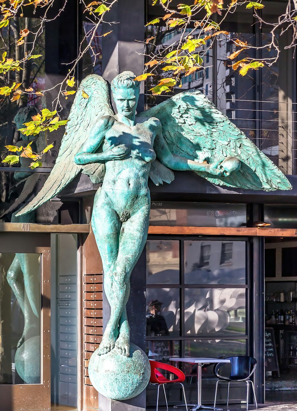 a statue of an angel holding a ball in front of a building