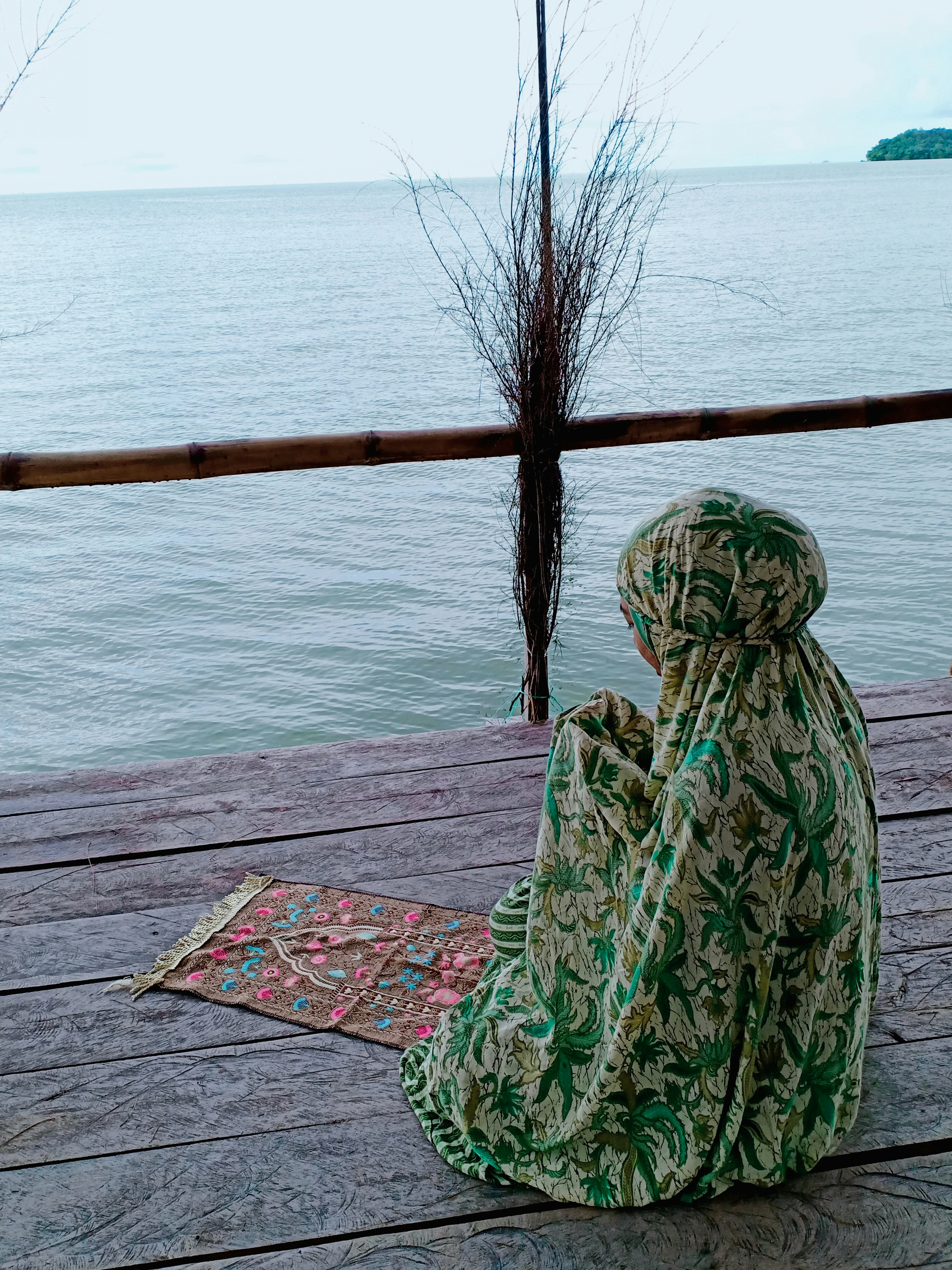 a woman sitting on a wooden deck next to a body of water