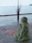 a woman sitting on a wooden deck next to a body of water