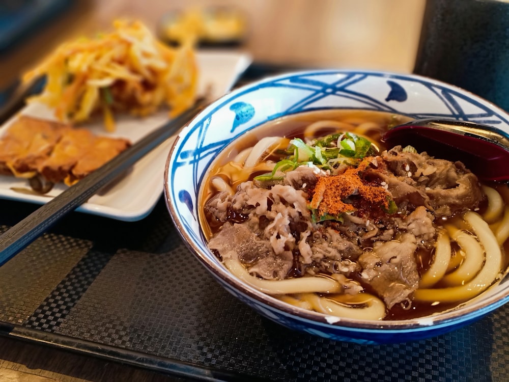 a blue and white bowl filled with noodles and meat
