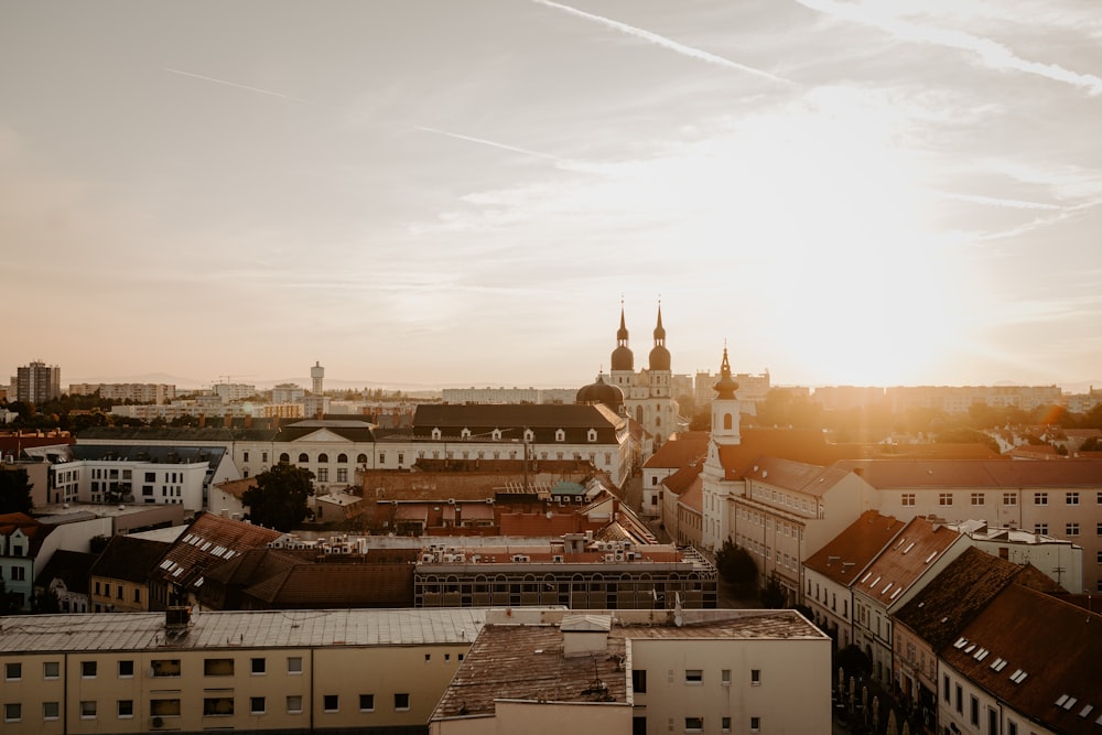 the sun is setting over a city with tall buildings