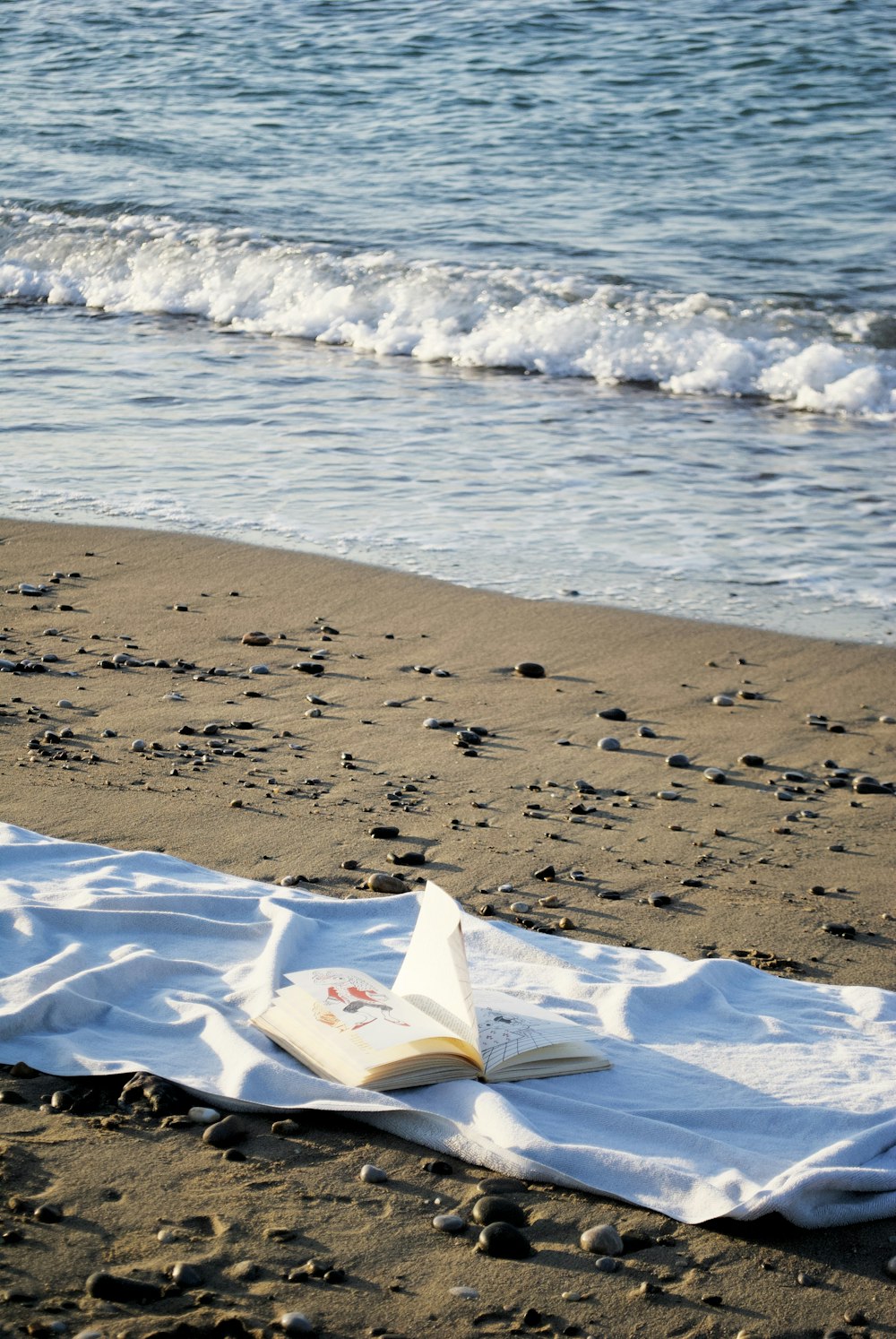 a book is laying on a towel on the beach