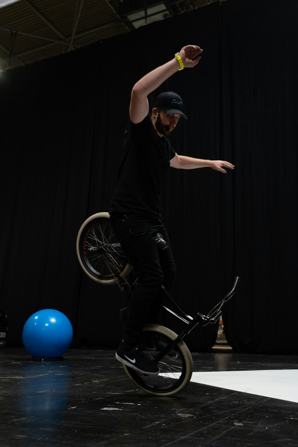 Un hombre montando una bicicleta encima de una pelota azul