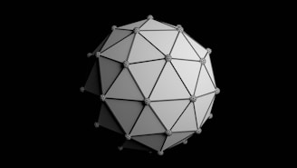 A geometric shape composed of interconnected triangular panels forms a complex three-dimensional polyhedron. Each vertex is adorned with a sphere, creating a pattern of connected nodes. The structure appears metallic and reflective against a black background.