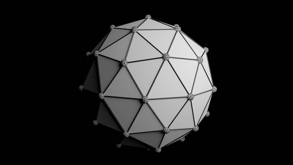 A geometric shape composed of interconnected triangular panels forms a complex three-dimensional polyhedron. Each vertex is adorned with a sphere, creating a pattern of connected nodes. The structure appears metallic and reflective against a black background.