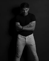 a man standing with his arms crossed in a black and white photo