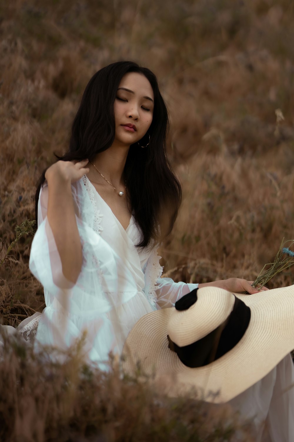 a woman sitting in a field with a hat