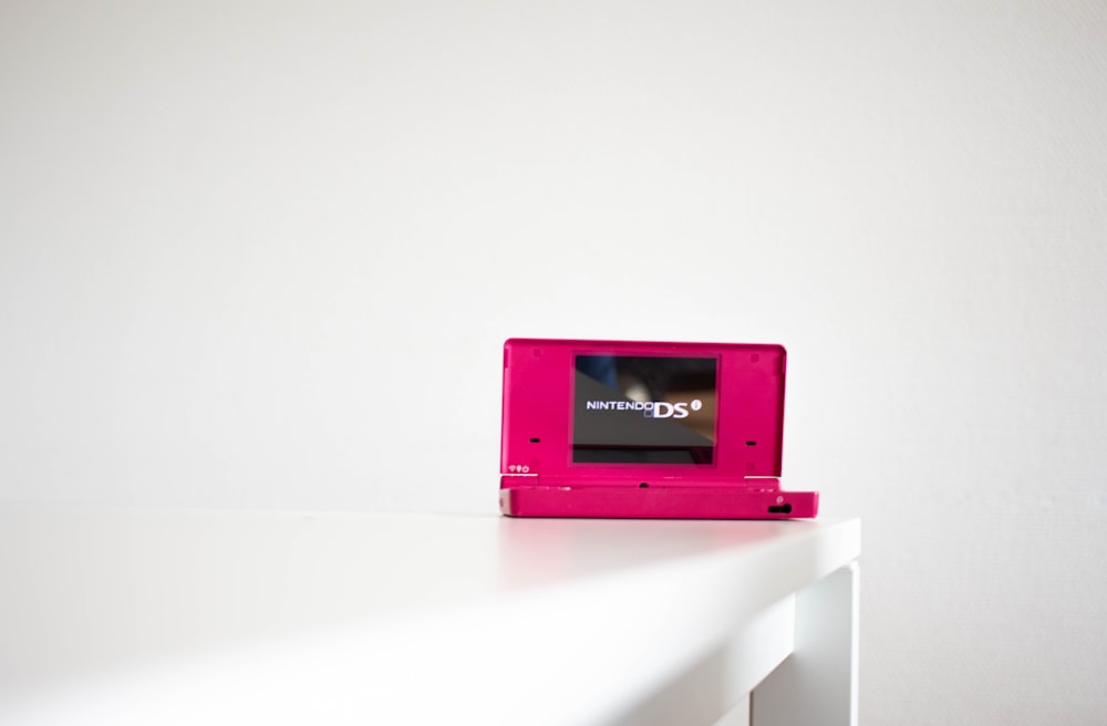 Un videojuego rosa sentado encima de una mesa blanca