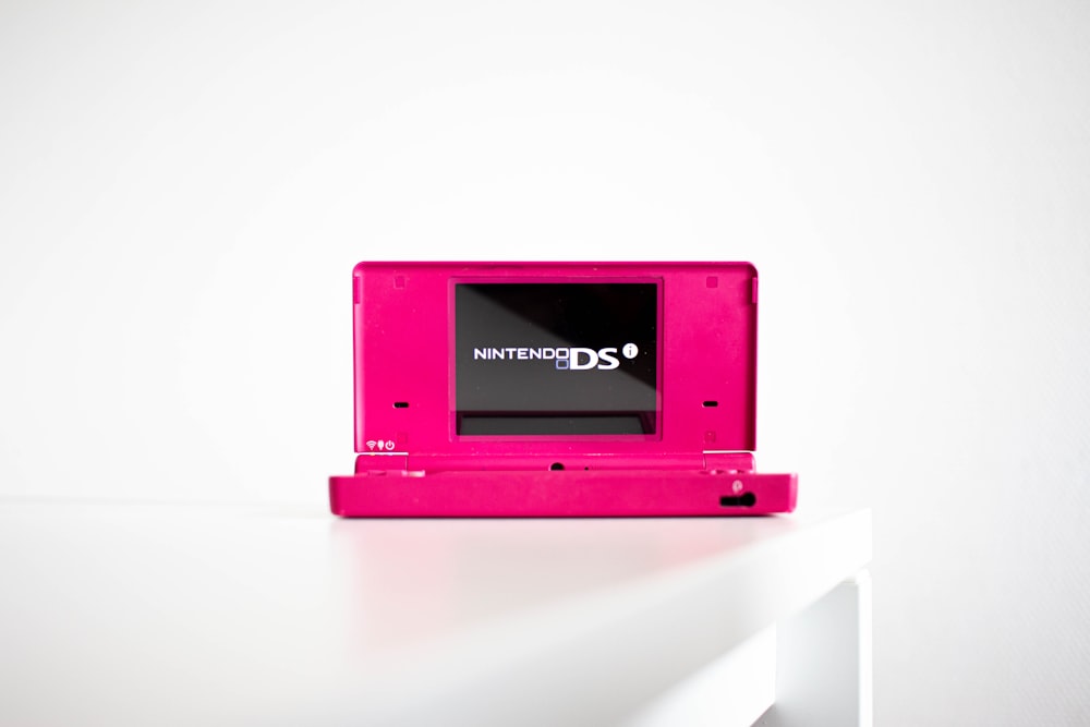a pink nintendo ds sitting on top of a white table